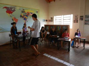 Here is my English class for kids with my older English student helping as assistant Profesor. This was while we were teaching colors; each child was given a paper with a color written in English on it and told to tape it to something in the room of the same color. Super fun day.